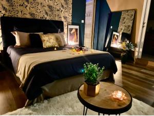 a bedroom with a large bed and a table with a plant at Love Room -La Suite Secrète in Rodez