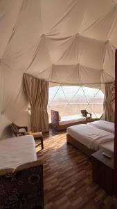 a bedroom with two beds and a large tent at Yazan Desert Camp in Wadi Rum