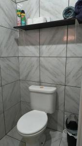 a bathroom with a toilet and a shelf with towels at Quarto 1 in Várzea Grande