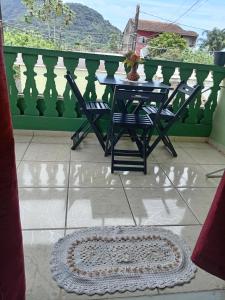 a table and chairs on a balcony with a rug at Belo Suítes in Ubatuba