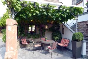 a patio with a table and chairs under a pergola at Wein- und Gästehaus M. Bai in Mesenich