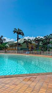 a large swimming pool with palm trees and a building at Maison Créole in Saint-François