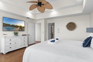 a bedroom with a white bed with a ceiling fan at Tidal Dreams Ocean Front Pool Firepit Sleeps 14 in Palm Coast +57 photos