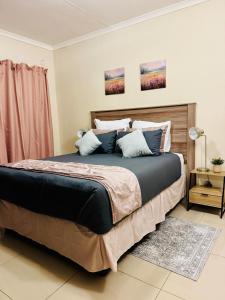 a bedroom with a large bed with blue pillows at Cozy 2-bedroom apartment in Gaborone