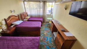 a room with two beds and a flat screen tv at Hotel San Felipe el Real in San Felipe