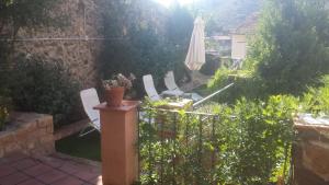 um pátio com um guarda-sol e cadeiras e um jardim em Can Peiri em Porrera