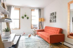 a living room with an orange couch and a table at 1597-PHS New 1BR-2bath PH Duplex Outdoor Deck in New York