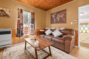a living room with a leather couch and a table at Hideaway Cabin - Cozy romantic cabin perfect for couples in Big Bear City