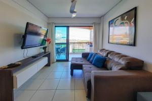 a living room with a couch and a flat screen tv at Beverly Hills 2 Suítes Apto Completo 500m Praia in Mangabeira
