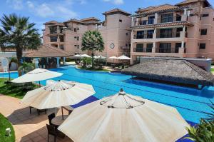 a swimming pool with umbrellas in front of a building at Beverly Hills 2 Suítes Apto Completo 500m Praia in Mangabeira