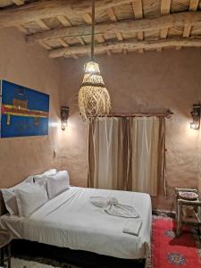 a bedroom with a bed and a chandelier at Maison d'hôte tamatart - Homestay in Kalaat MGouna
