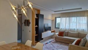 a living room with a couch and a tv at Bel appartement familial résidence sécurisée in Casablanca