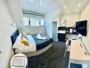 a bedroom with a bed and a desk with a computer at gwesTY Guest House in Aberystwyth