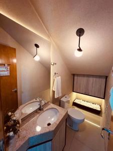 a bathroom with a sink and a toilet and lights at Moderno Sobrado Climatizado com Ar Quente e Frio in Cascavel +50 photos