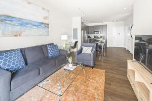 a living room with a gray couch and a living room with a kitchen at Global Luxury Suites at Reston in Reston