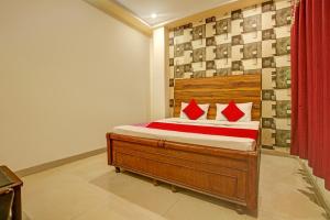 a bedroom with a wooden bed with red pillows at Hotel O NR Residency in Banūr