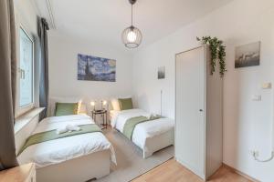 zwei Betten in einem Zimmer mit weißen Wänden in der Unterkunft Eco Retreat Spacestays - Smart TV - WIFI in Essen
