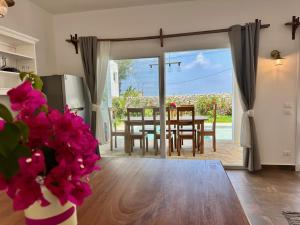 una cucina e una sala da pranzo con tavolo e fiori rosa di Beachfront Alma Villa with Private Pool ZanzibarHouses a Kiwengwa