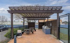 Sleepover 1BD 1BA Corpus Christi Apartments في كوربوس كريستي: بريغولا خشبي مع طاولة نزهة ومقعد