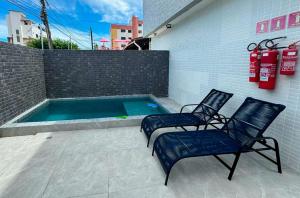 zwei Stühle und ein Pool neben einem Gebäude in der Unterkunft Charmoso Bessa 200m da Praia 2 Quartos 5 Pessoas in Nossa Senhora do Livramento