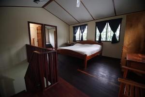 a small bedroom with a bed and two windows at Pavones Point Surf House in Great Location in Pavones