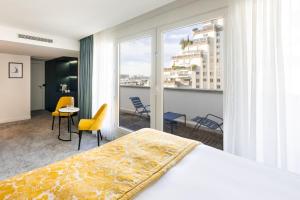 a bedroom with a bed and a balcony with chairs at voco Paris Montparnasse by IHG in Paris +107 photos