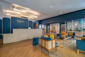 a lobby with blue and yellow chairs and a table at voco Paris Montparnasse by IHG in Paris