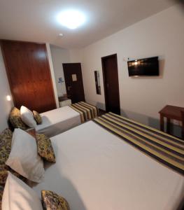 a hotel room with two beds and a television at Hotel Giordano Centro in São João da Boa Vista