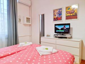 a bedroom with a pink polka dot bed and a tv at Family Apartment next to National Palace of Culture in Sofia
