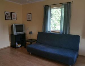 a living room with a blue couch and a tv at Domek nad jeziorem Węgorzyno in Augustowo