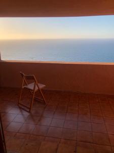 Una silla sentada en una habitación mirando al océano. en The Belvedere di Achille, en Costa Paradiso