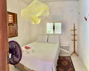 a bedroom with a bed with a fan and a window at Casa Branca in Atins