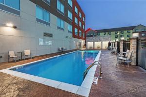 a swimming pool with chairs and a building at Holiday Inn Express & Suites - Tulsa Northeast - Owasso by IHG in Owasso