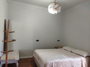 a bedroom with a white bed and a chandelier at Pousada Guaíra in Guaíra