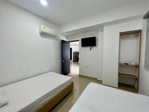 a white room with two beds and a television at Apartamentos VIOLETTA in Cereté