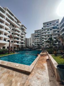 a swimming pool in front of some apartment buildings at Appartement Vue Mer & Coucher de Soleil in Aïn Harrouda