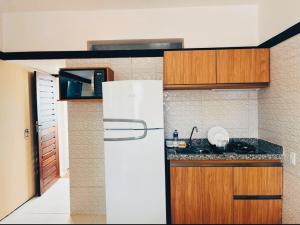 a kitchen with a white refrigerator and wooden cabinets at Vista Maravilhosa 706 in Fortaleza