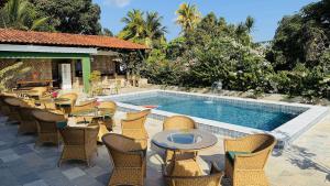 a patio with tables and chairs next to a swimming pool at Hotel Pousada Flor de Alecrim - Goiana in Goiana
