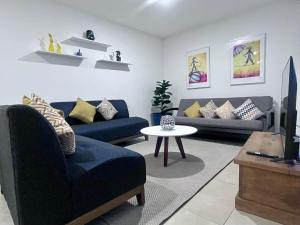 ein Wohnzimmer mit zwei blauen Sofas und einem Fernseher in der Unterkunft ML002 - 2BR - 2BTh in Mexiko-Stadt
