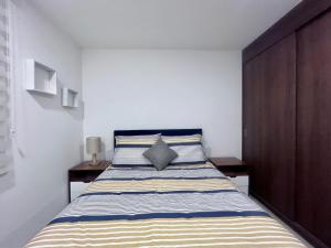 ein Schlafzimmer mit einem großen Bett und einer gestreiften Tagesdecke in der Unterkunft ML002 - 2BR - 2BTh in Mexiko-Stadt