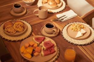 a wooden table with plates of food and cups of coffee at Talam House Coveñas by Bernalo Hotels in Coveñas