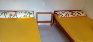 two beds in a small room with yellow beds at Sítio do Dindinho - Aiurê in Grão Pará