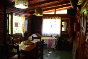 a room with a table and a bed and windows at Mainame Traslasierra in Los Hornillos