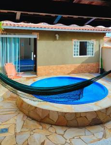 a hammock in front of a house with a pool at Casa Espaço Sara Piscina Aquecimento Solar total privacidade, área gourmet completa com churrasqueira fogão a lenha, a 5min do centro e do parque das águas in São Lourenço