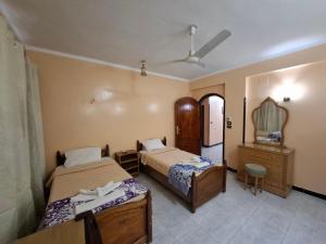 1 dormitorio con 2 camas, tocador y espejo en West Bank Guest House, en Luxor