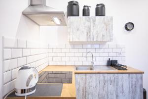 a white kitchen with a sink and a mixer at Apartamenty Stacja Kasina in Kasina Wielka