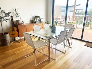 a dining room with a table and chairs and a guitar at Bright, spacious apartment in Torquay in Torquay