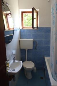 La salle de bains est pourvue de carrelage bleu, de toilettes et d'un lavabo. dans l'établissement Apartments Nev, à Blato
