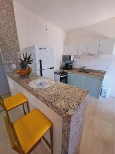 a kitchen with a counter and a yellow stool at Linda Casa Linear Com PISCINA, Buzios in Buzios