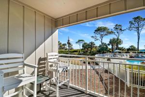 a balcony with two chairs and a swimming pool at Ocean Dunes Villas #111, Beach Condo in Coligny Beach, 43 S Forest Beach Dr, Hilton Head SC, Oceanfront condo, Heated Pool, By Vacation Rental HHI in Hilton Head Island